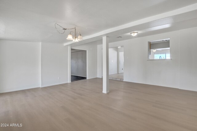 basement with ceiling fan with notable chandelier and hardwood / wood-style floors