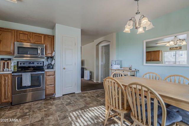 11101 E Abilene Ave, Mesa, AZ 85208 - kitchen featuring appliances with stainless steel finishes, a chandelier, arched walkways, brown cabinetry, and stone finish floors