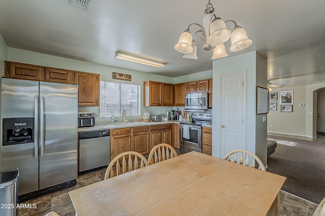11101 E Abilene Ave, Mesa, AZ 85208 - kitchen with stainless steel appliances, light countertops, brown cabinets, a chandelier, and arched walkways