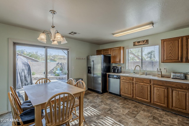 11101 E Abilene Ave, Mesa, AZ 85208 - kitchen featuring stainless steel appliances, a chandelier, light countertops, brown cabinetry, and pendant lighting