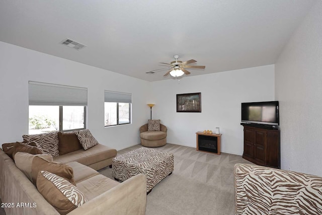 carpeted living room with a fireplace and ceiling fan