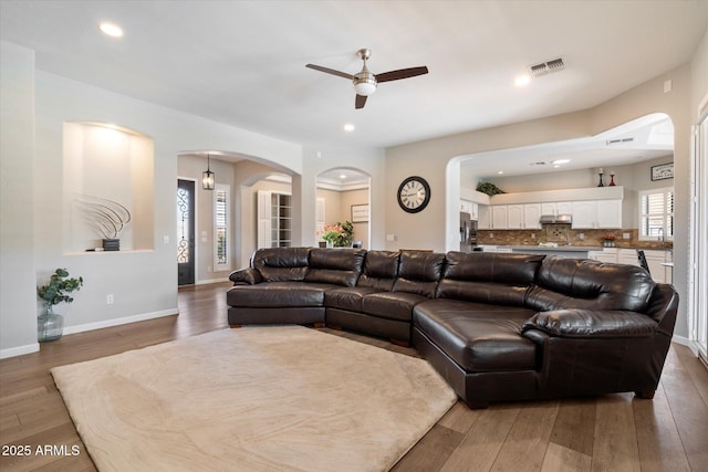 24403 N 43rd Dr, Glendale, AZ 85310 - living room featuring a ceiling fan, visible vents, a healthy amount of sunlight, arched walkways, and hardwood / wood-style flooring