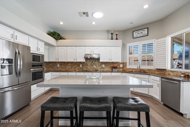 24403 N 43rd Dr, Glendale, AZ 85310 - kitchen featuring under cabinet range hood, visible vents, a kitchen bar, stainless steel appliances, and a sink