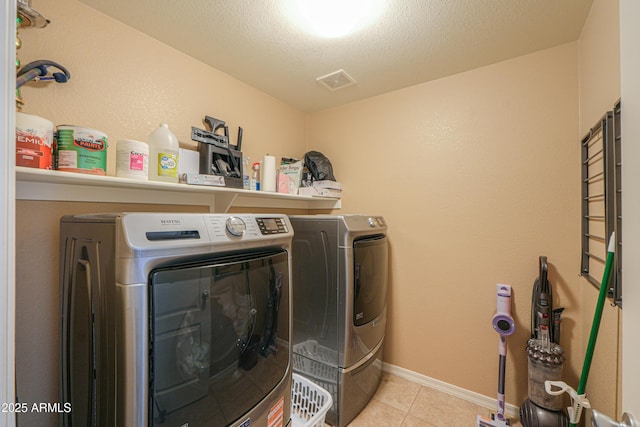 laundry room featuring laundry area, tile patterned flooring, a textured ceiling, baseboards, and washer and clothes dryer