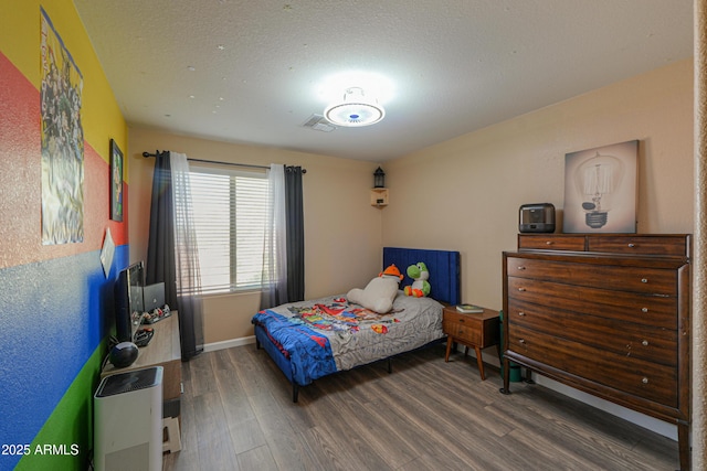 bedroom featuring baseboards, wood finished floors, and visible vents