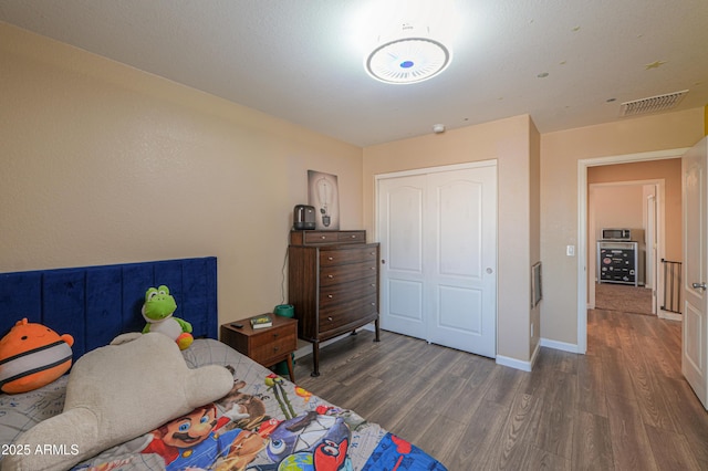 bedroom with baseboards, wood finished floors, and visible vents