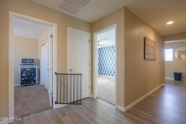 hallway with recessed lighting, baseboards, visible vents, and wood finished floors