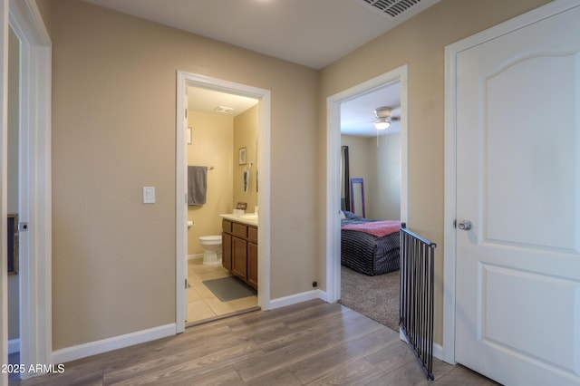 corridor with baseboards, light wood-style flooring, and visible vents
