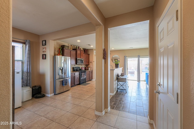 interior space with brown cabinetry, baseboards, tasteful backsplash, appliances with stainless steel finishes, and light tile patterned floors