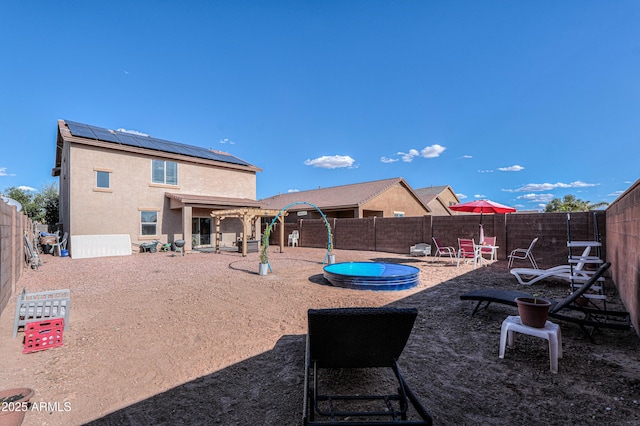 back of property with a fenced backyard, a patio area, stucco siding, and solar panels