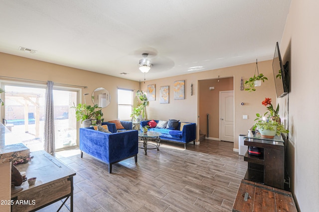 living room with ceiling fan, visible vents, baseboards, and wood tiled floor