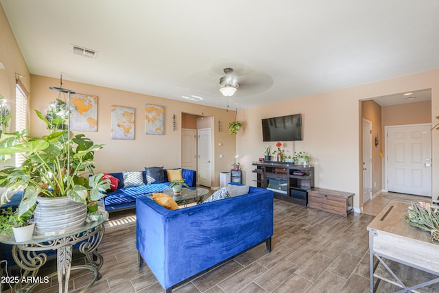 living area with wood tiled floor, ceiling fan, baseboards, and visible vents