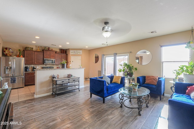 living area featuring ceiling fan, visible vents, baseboards, and wood tiled floor