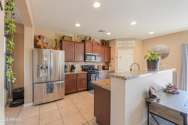 kitchen with backsplash, brown cabinets, appliances with stainless steel finishes, and visible vents