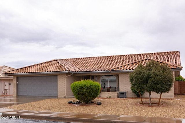 view of front of home with brick siding, concrete driveway, an attached garage, and a tiled roof