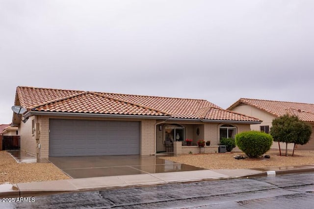 view of front of property with a tile roof, concrete driveway, brick siding, and a garage