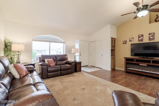 living room featuring a ceiling fan, wood finished floors, baseboards, and high vaulted ceiling