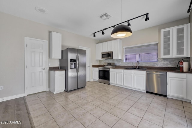 1090 S Bogle Ct, Chandler, AZ 85286 - kitchen with stainless steel appliances, track lighting, dark countertops, tasteful backsplash, and glass insert cabinets