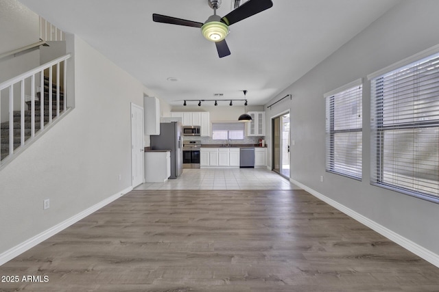 1090 S Bogle Ct, Chandler, AZ 85286 - unfurnished living room with a ceiling fan, light wood finished floors, stairway, and track lighting