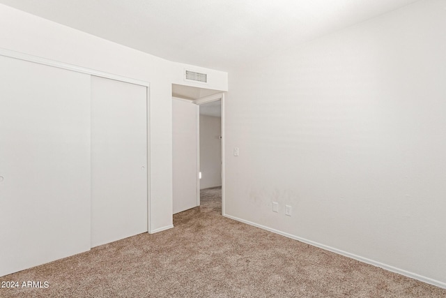 unfurnished bedroom featuring a closet and light colored carpet