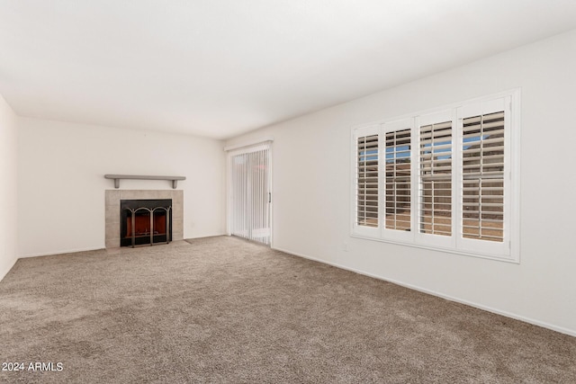 unfurnished living room featuring a tiled fireplace and carpet floors