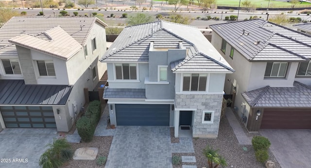 view of front of home featuring stone siding, stucco siding, driveway, and an attached garage