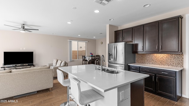 kitchen featuring visible vents, wood tiled floor, a sink, stainless steel fridge, and open floor plan