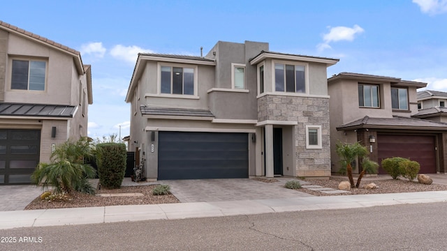 view of front of property featuring stone siding, stucco siding, an attached garage, and decorative driveway