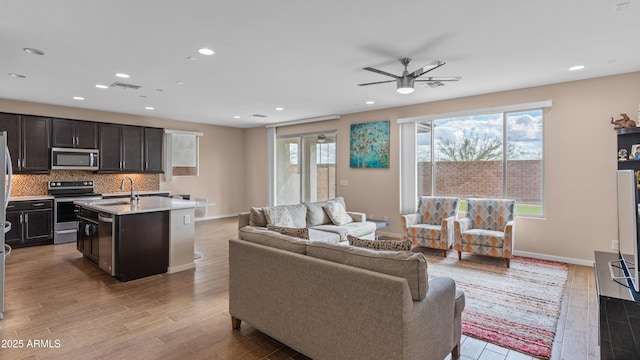 living area featuring plenty of natural light, light wood finished floors, and ceiling fan