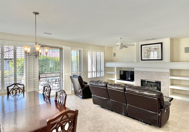 living room with ceiling fan with notable chandelier and a premium fireplace