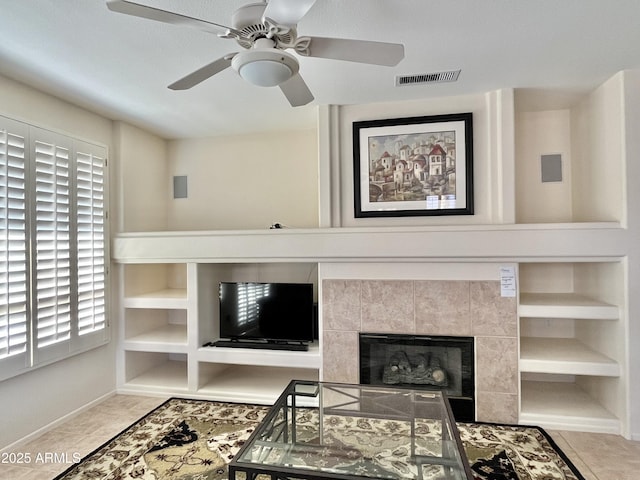 living room featuring a tiled fireplace, light tile patterned floors, and built in shelves