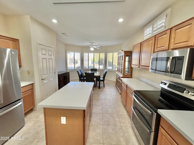 kitchen with light tile patterned flooring, ceiling fan, stainless steel appliances, and a center island