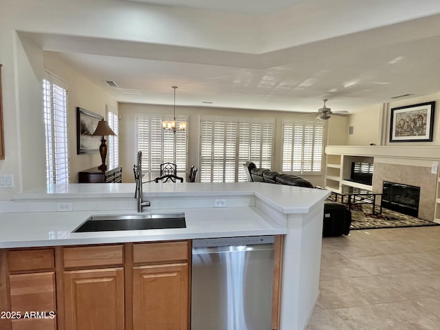 kitchen with sink, stainless steel dishwasher, a wealth of natural light, pendant lighting, and a high end fireplace