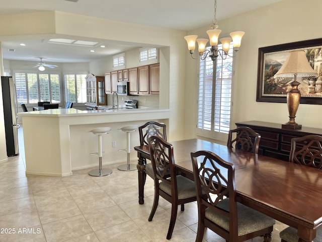 tiled dining area featuring sink and ceiling fan with notable chandelier