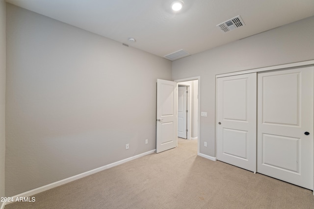 unfurnished bedroom featuring light colored carpet and a closet