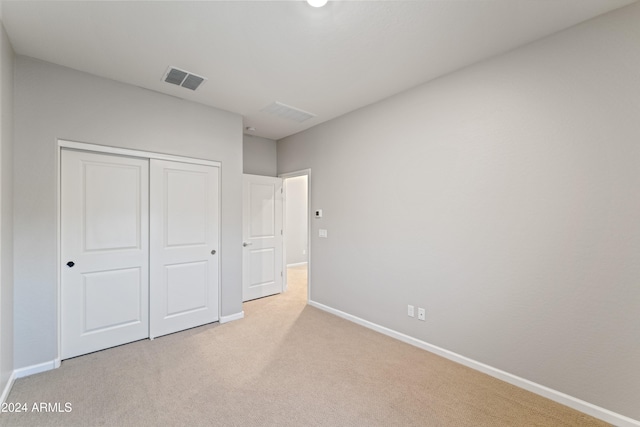 unfurnished bedroom with light carpet and a closet