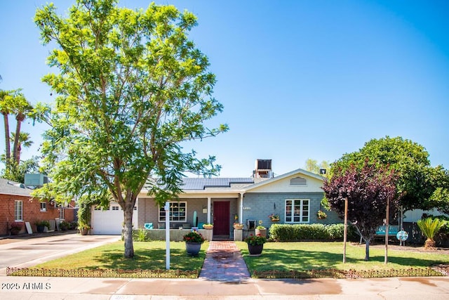 view of front of home featuring a garage, a front lawn, and solar panels