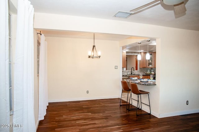 kitchen with dark hardwood / wood-style flooring, sink, decorative light fixtures, a breakfast bar, and decorative backsplash