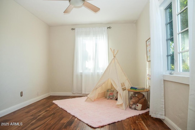 rec room featuring a healthy amount of sunlight, ceiling fan, and dark hardwood / wood-style flooring