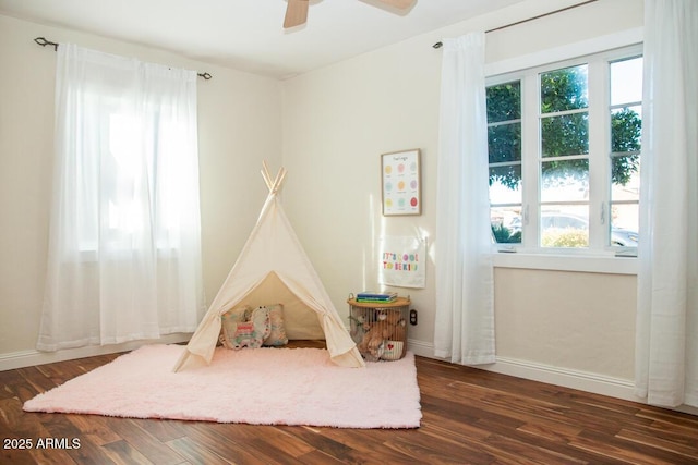 game room with ceiling fan, a healthy amount of sunlight, and dark hardwood / wood-style floors