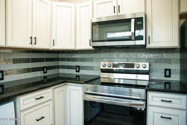 kitchen featuring decorative backsplash, white cabinets, appliances with stainless steel finishes, and dark stone counters