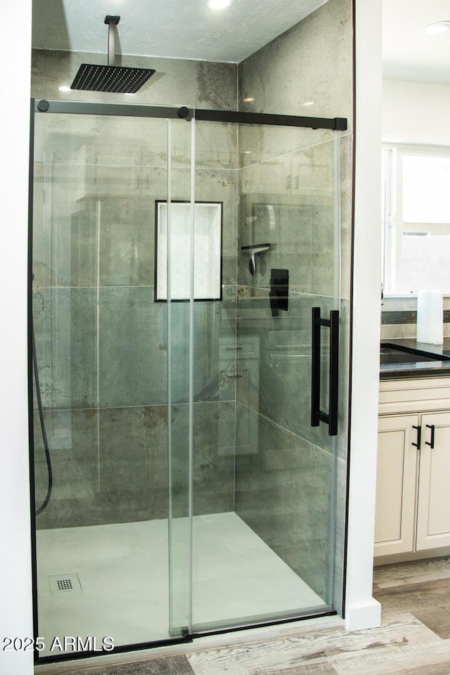 bathroom featuring wood-type flooring, a shower with door, and vanity