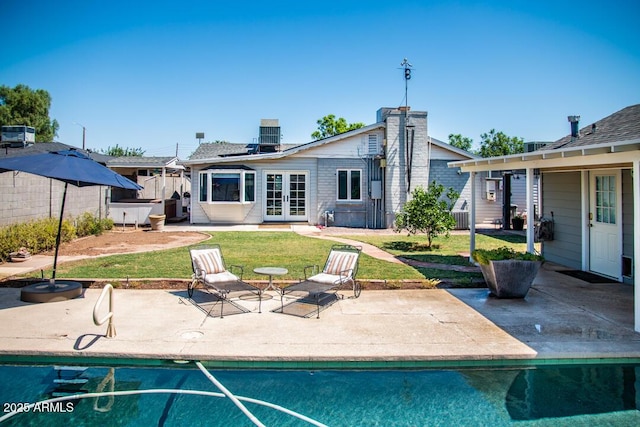 back of property with a lawn, a patio, solar panels, and french doors