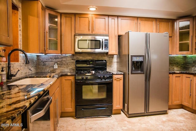 kitchen with tasteful backsplash, sink, stainless steel appliances, and dark stone countertops