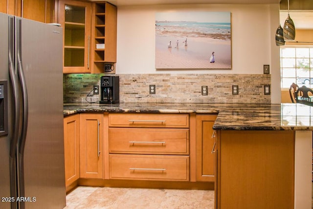 kitchen featuring backsplash, dark stone counters, and stainless steel fridge