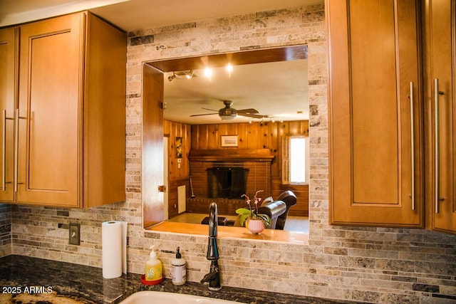 kitchen with ceiling fan, backsplash, sink, and a brick fireplace