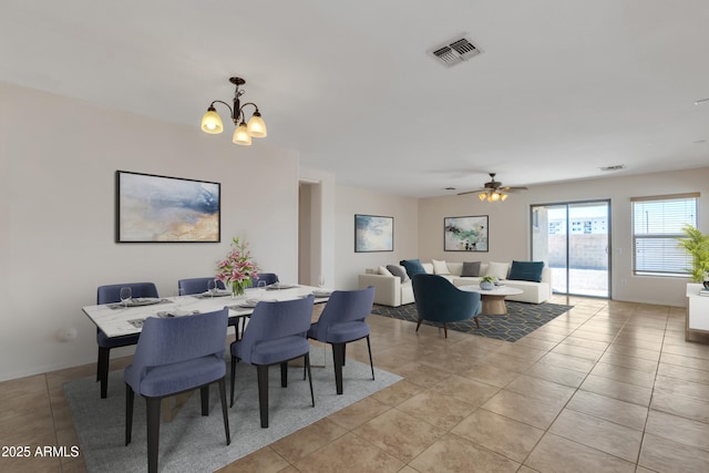 dining area featuring ceiling fan with notable chandelier, light tile patterned floors, baseboards, and visible vents