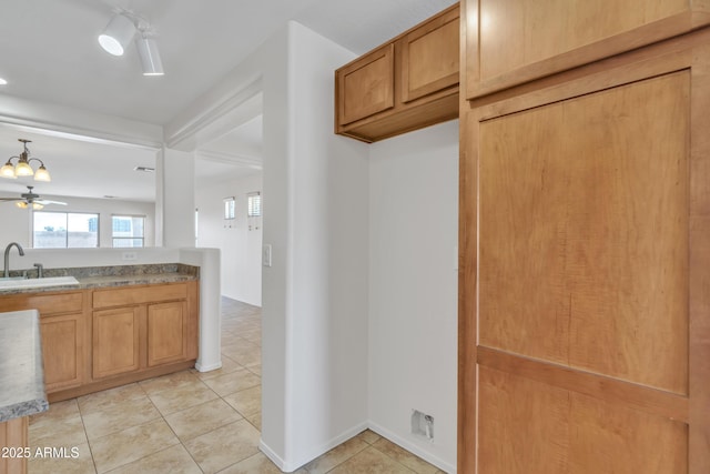kitchen with a sink, light tile patterned floors, and ceiling fan