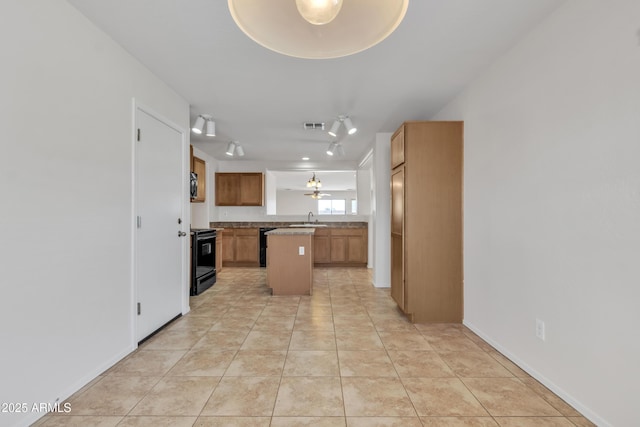 kitchen featuring black stove, a center island, light tile patterned flooring, visible vents, and a sink