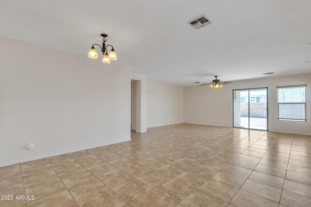 empty room with ceiling fan with notable chandelier, light tile patterned flooring, and visible vents